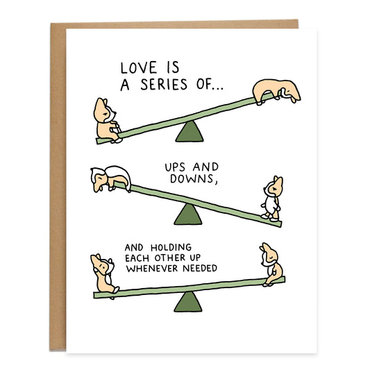 three seesaws with two corgis on each side laying down and sitting up at different levels and moods, text on card reads: love is a series of ups and downs, and holding each other up whenever needed