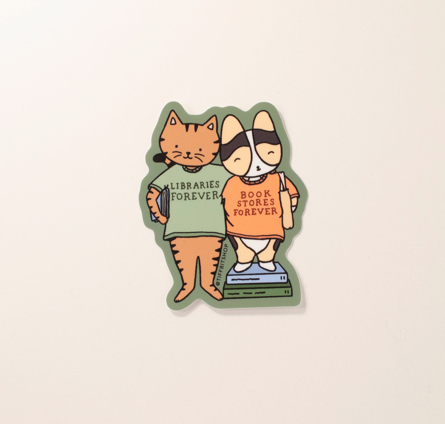 On a forest green background with a drawing of a brown tabby cat holding a book under their arm wearing a green shirt that says, libraries forever. The cat has its arm around a tricolor corgi wearing a tote bag and standing on top of stacked books and wearing an orange shirt that says, bookstores forever