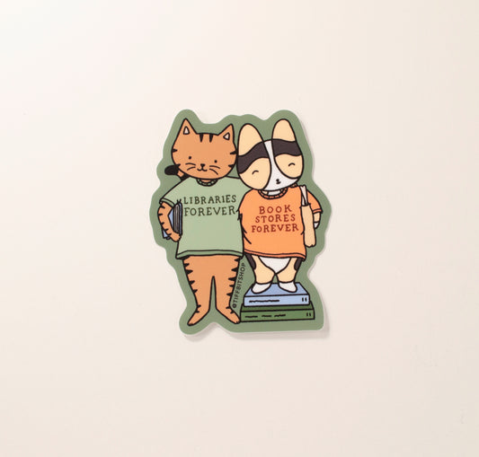 On a forest green background with a drawing of a brown tabby cat holding a book under their arm wearing a green shirt that says, libraries forever. The cat has its arm around a tricolor corgi wearing a tote bag and standing on top of stacked books and wearing an orange shirt that says, bookstores forever