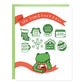 A greeting card with an illustration of a cute frog drinking tea looking up at holiday motifs with matching text that read, 'Medicare for all (stocking), Tax the rich (gift box), Clean air & water (globe), Fund libraries (calendar), Housing as a human right (Hot chocolate mug), Abolish ICE (snowflake), Land back (ginger bread house), Bombs (the word crossed out inside of a round ornament). The card has a red ribbon design with white text written, 'It's Timeeeeeeee'