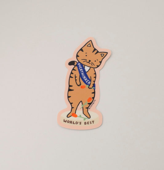 A drawing of a brown tabby cat with its head tilted, standing on a podium that reads, World's Best, and wearing a sash that reads, Overthinker