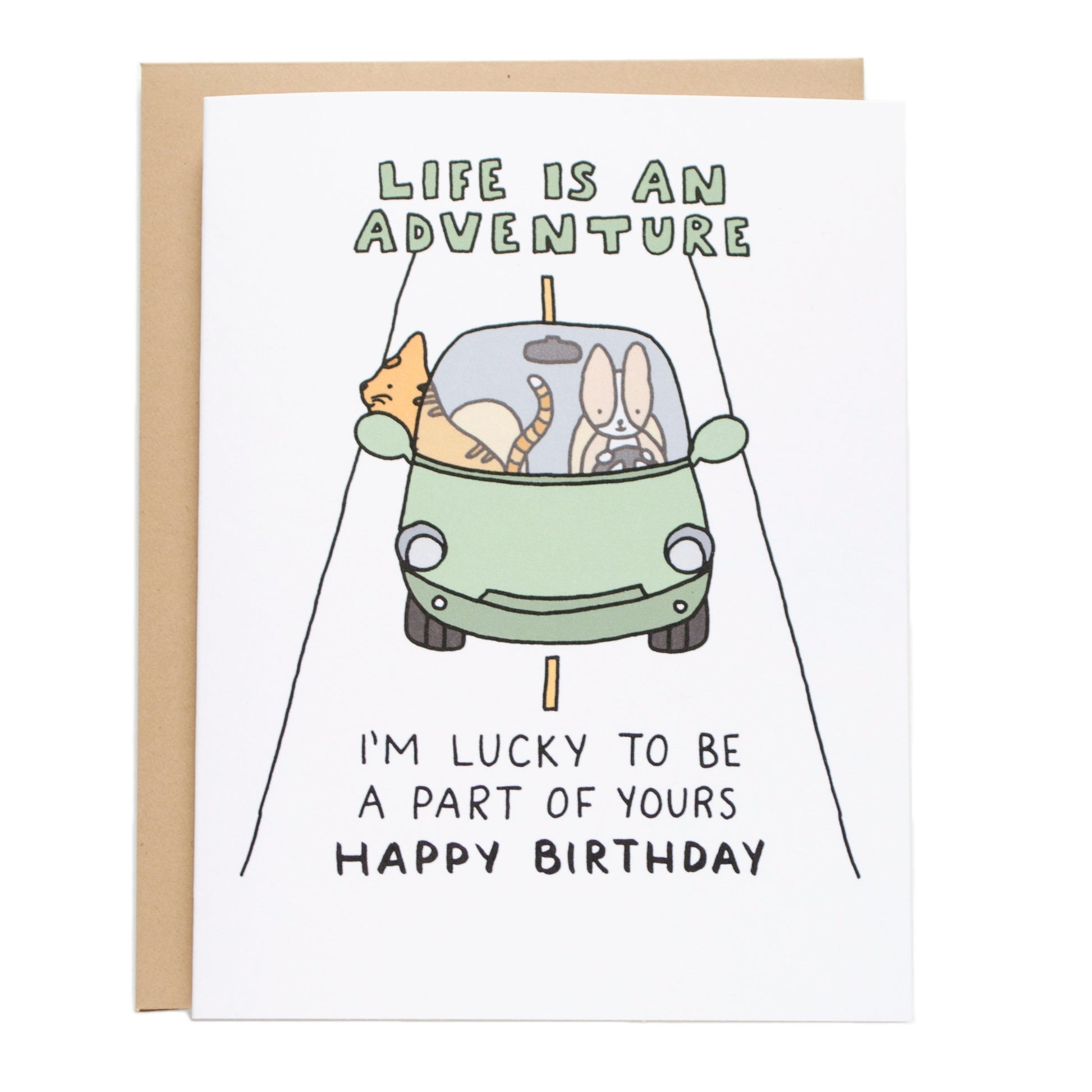 a orange tabby cat in the passenger side with its head out of the car with a corgi driving down a road, the card reads, life is an adventure, i'm lucky to be a part of yours, happy birthday