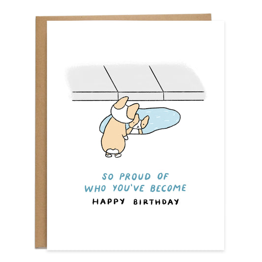 a drawing of a corgi smiling and looking at their reflection in a puddle of water next to the sidewalk, card reads, so proud of who you've become, happy birthday
