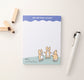 A notepad design with a swiggly blue header on top with the words, you are doing amazing, in white. On the bottom are three corgis pointing at each other with a date field next to them
