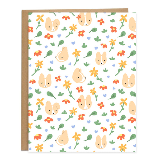 a pattern of corgi heads looking around with blue hearts, leaves, and red and orange flowers floating around