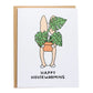 corgi holding monstera plant covering parts of his face, card reads, happy housewarming
