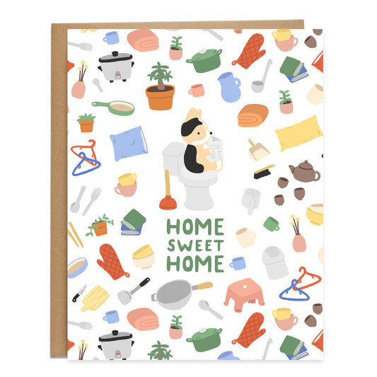 A tricolor corgi sitting on the toilet reading a newspaper in the center, surrounded by a pattern of homewares like kitchen tools, teapot and cups, rice cooker, wok, pots, plants, and cups. Card reads, Home sweet home, in green bubbly handwriting