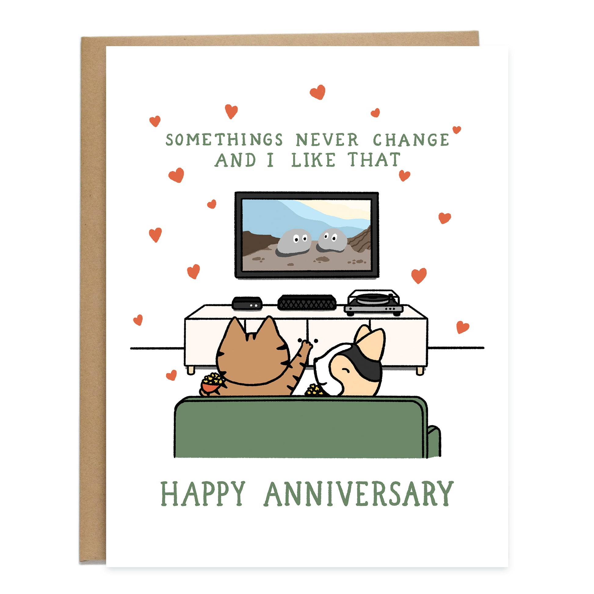 A card with a drawing of a cat and corgi at home watching a movie on the tv on their green couch, eating popcorn. The cat is pointing at the tv, with the movie EEAAO playing. The card reads, somethings never change and I like that, happy anniversary