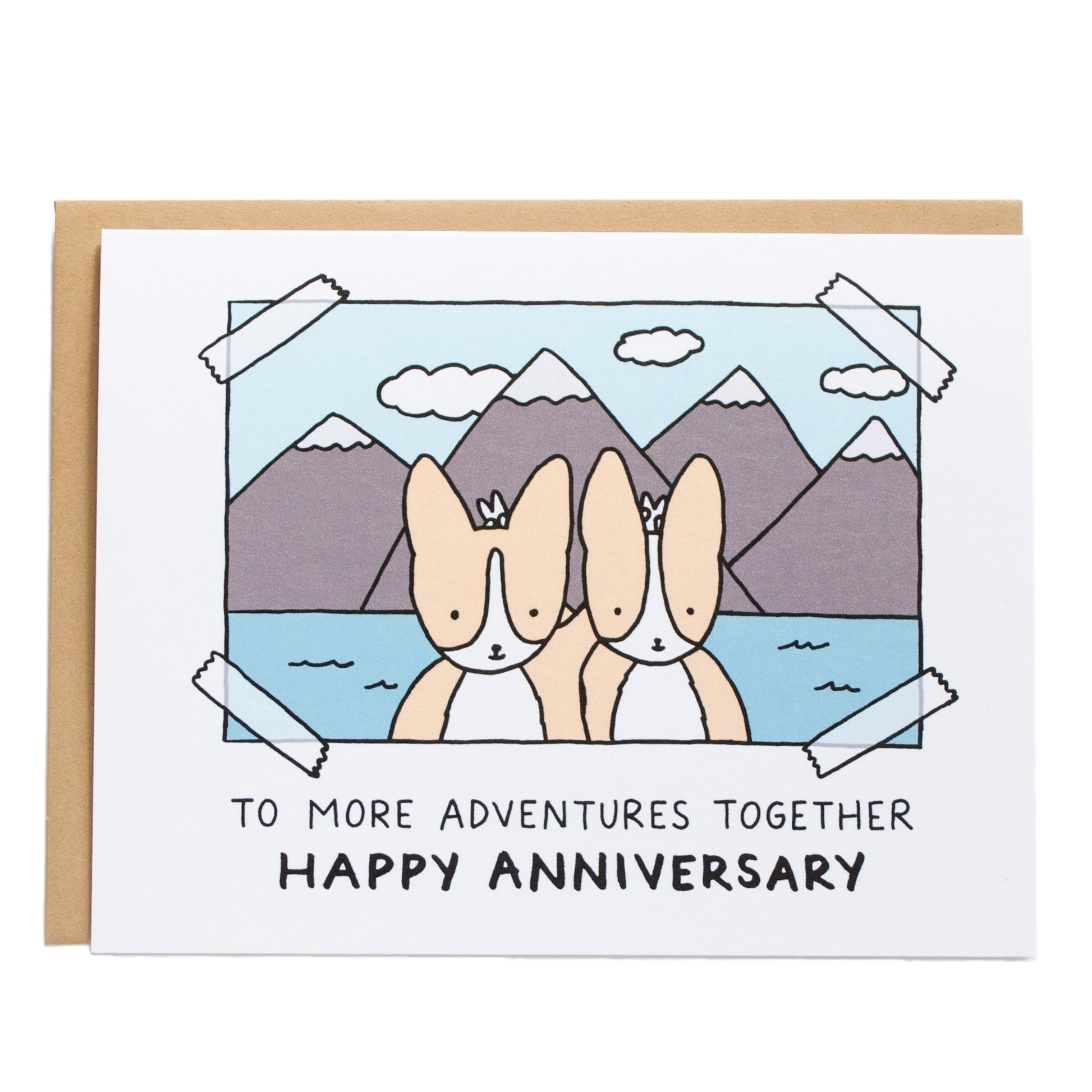 a taped photograph of two corgis putting bunny ears on each other in front of a scenic background of mountains, card reads, to more adventures together, happy anniversary