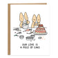 two corgis baking making a mess with a cake that looks pretty covered in pink icing but is crooked, one corgi looks one happily and the other unsure, text on card reads: our love is a piece of cake