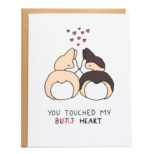 two corgis looking at each other with their butts (a tan and tricolor corgi) facing the front and their noses booping. card reads, you touched my (butt, is crossed out) heart