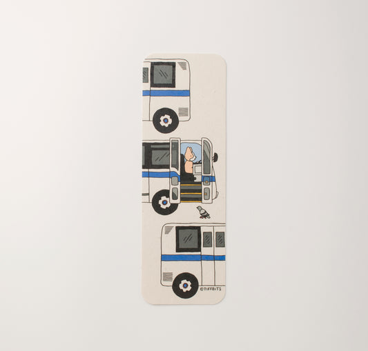 A bookmark of a corgi driving an nyc bus train with a pigeon standing at the open door. The design shows three buses stacked on top of each other (top: the end of the bus, middle: front, bottom: end)
