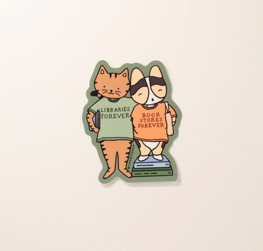 On a forest green background with a drawing of a brown tabby cat holding a book under their arm wearing a green shirt that says, libraries forever. The cat has its arm around a tricolor corgi wearing a tote bag and standing on top of stacked books and wearing an orange shirt that says, bookstores forever