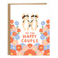 Two tricolor corgis with a flower on their heads and holding hands in the center surrounded by red, pink, and cornflower blue flowers surrounding them of different sizes. Card reads, to the happle couple, in red handwriting